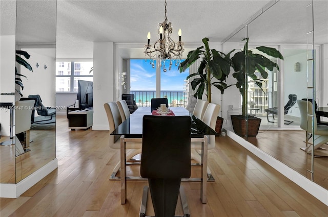 dining space featuring a notable chandelier, light hardwood / wood-style floors, and a textured ceiling