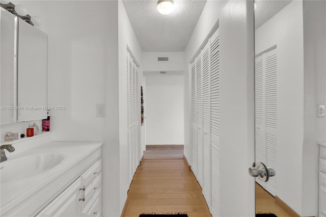 bathroom with wood-type flooring, vanity, and a textured ceiling