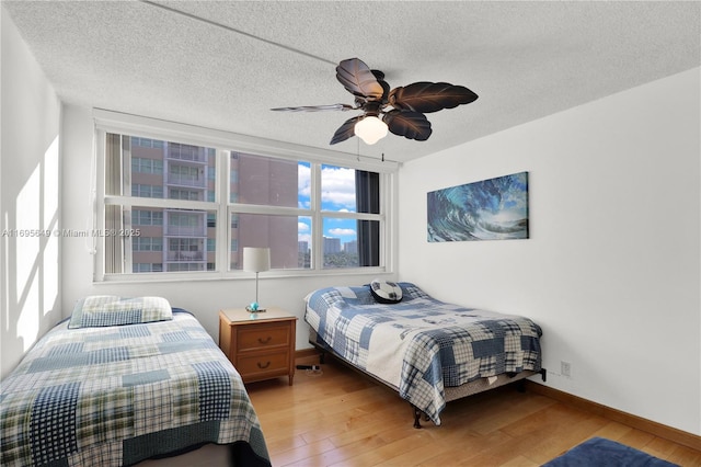 bedroom featuring ceiling fan, hardwood / wood-style flooring, and a textured ceiling