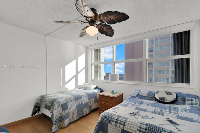 bedroom with ceiling fan, light hardwood / wood-style flooring, and a textured ceiling