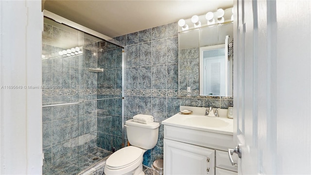 bathroom featuring vanity, toilet, an enclosed shower, and tile walls