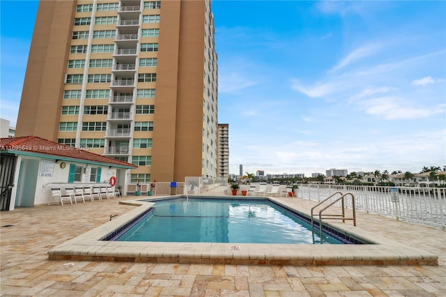 view of pool featuring a water view and a patio