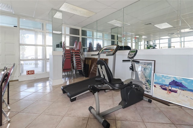 exercise area featuring a healthy amount of sunlight, light tile patterned floors, and a drop ceiling