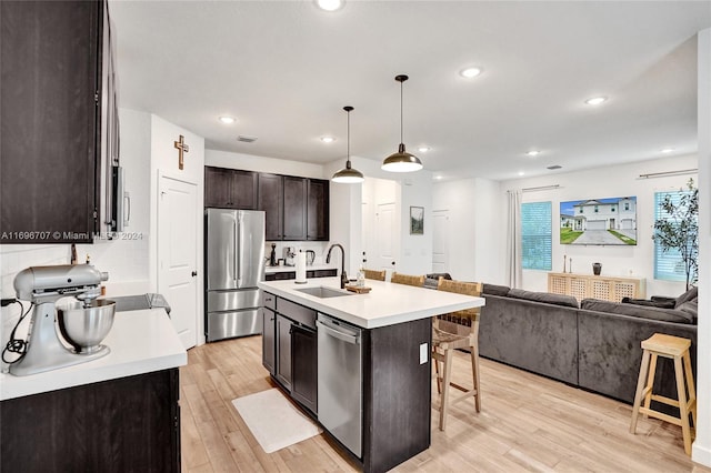 kitchen featuring sink, stainless steel appliances, a kitchen breakfast bar, an island with sink, and pendant lighting