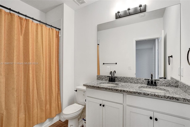 full bathroom featuring hardwood / wood-style floors, vanity, shower / tub combo, and toilet