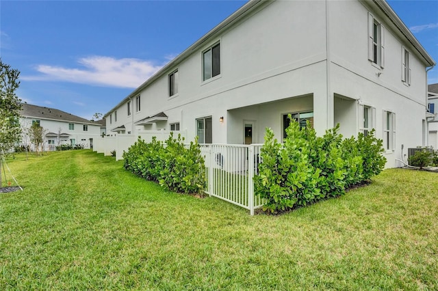 rear view of house with a lawn and central AC