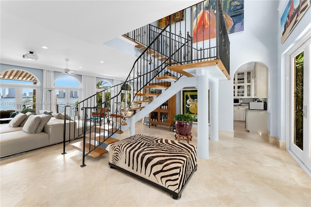 stairs featuring ceiling fan, french doors, and a high ceiling