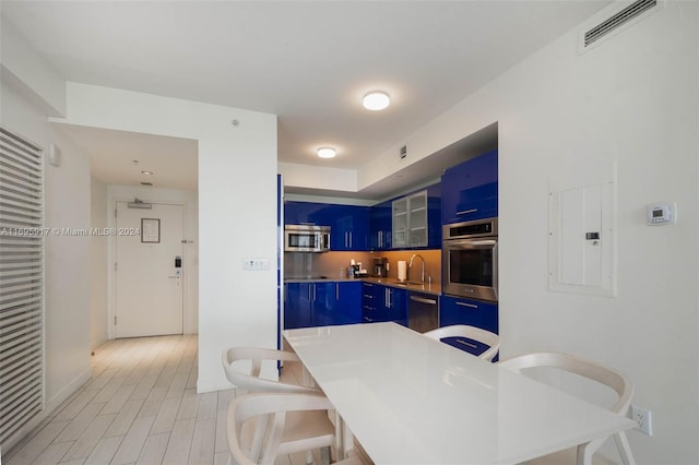 kitchen with blue cabinetry, electric panel, sink, and appliances with stainless steel finishes