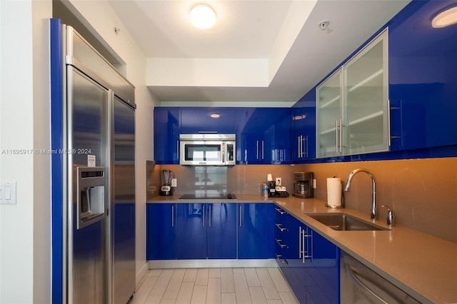 3101 Bayshore Dr Unit 1602, Fort Lauderdale, FL 33304 - kitchen with stainless steel appliances, a sink, blue cabinetry, glass insert cabinets, and light countertops
