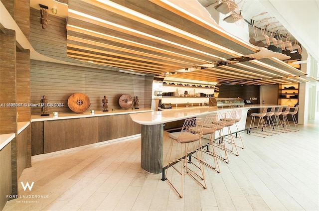 bar with light hardwood / wood-style floors and wooden walls