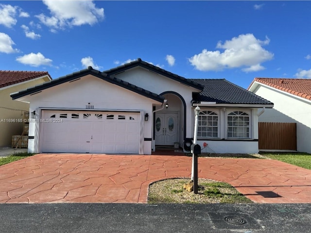 single story home with an attached garage, driveway, a tiled roof, and stucco siding