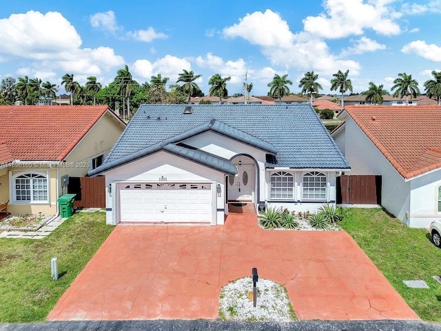 view of front of house with concrete driveway, fence, a tiled roof, and an attached garage