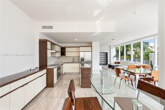 kitchen featuring wall chimney exhaust hood, white cabinetry, sink, and appliances with stainless steel finishes