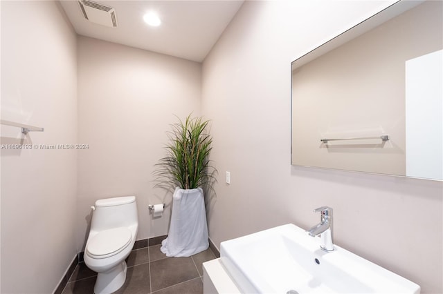 bathroom with toilet, sink, and tile patterned flooring