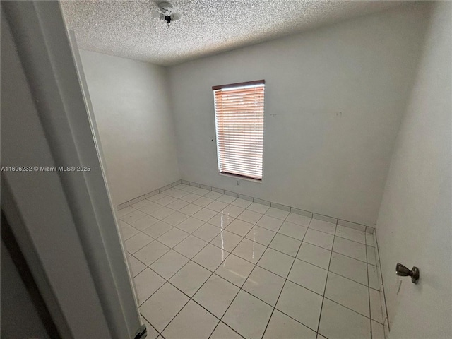 tiled empty room featuring a textured ceiling