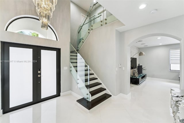 tiled foyer entrance featuring french doors and a notable chandelier