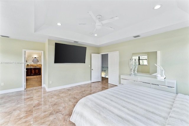 bedroom with ceiling fan, a raised ceiling, and ensuite bathroom