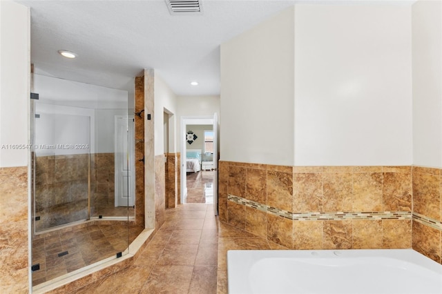 bathroom featuring tile walls, tile patterned flooring, a bath, and a textured ceiling