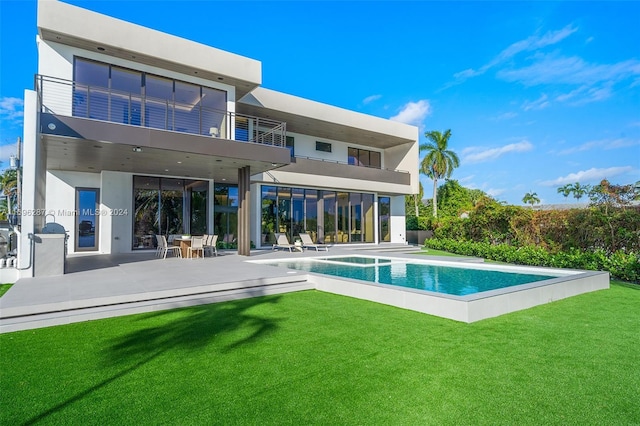 back of property with a yard, a patio, a balcony, and a pool with hot tub