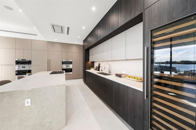 kitchen with a large island, sink, tasteful backsplash, wine cooler, and a water view