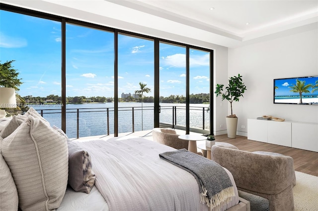 bedroom with a water view and hardwood / wood-style flooring