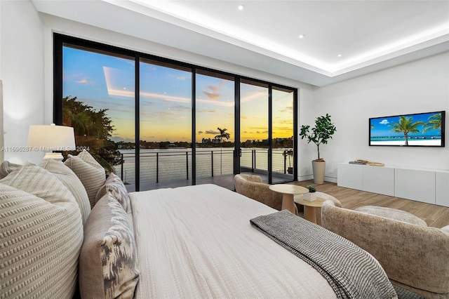 bedroom featuring multiple windows, access to outside, and hardwood / wood-style flooring