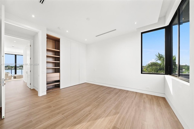 unfurnished bedroom featuring a water view and light wood-type flooring