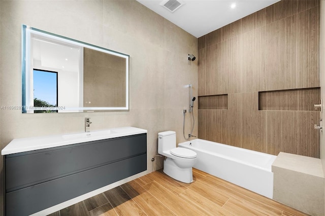 full bathroom featuring vanity, shower / washtub combination, wood-type flooring, tile walls, and toilet