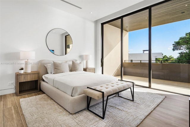 bedroom with access to exterior, light hardwood / wood-style flooring, and floor to ceiling windows