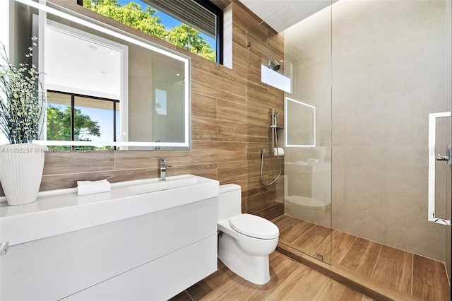 bathroom with hardwood / wood-style floors, toilet, a healthy amount of sunlight, and a tile shower