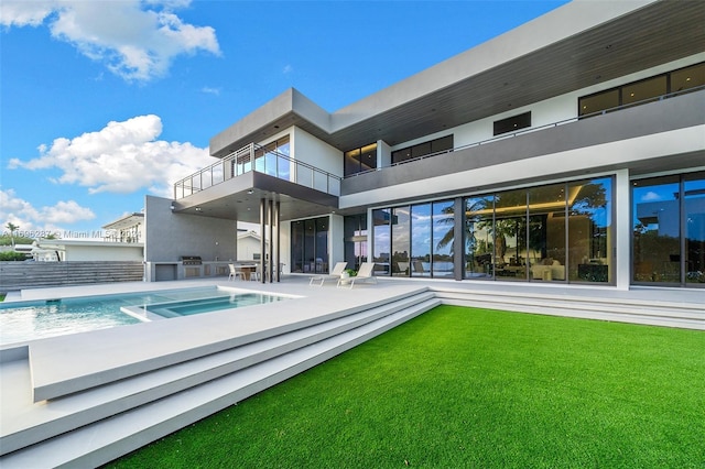 back of property with a lawn, an outdoor kitchen, and a patio