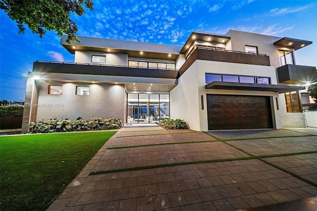 contemporary house featuring a lawn, a balcony, and a garage