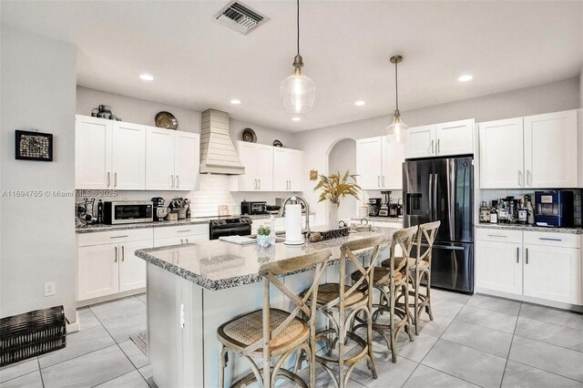 kitchen featuring white cabinets, custom range hood, and stainless steel appliances