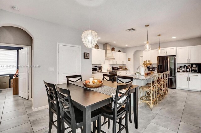 dining area with light tile patterned floors, ceiling fan with notable chandelier, and a tray ceiling