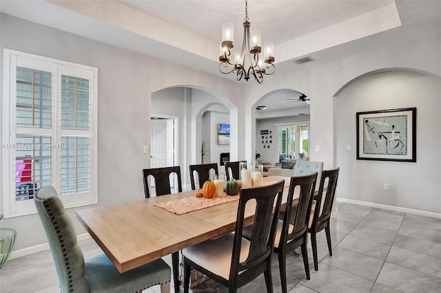 dining area featuring ceiling fan with notable chandelier and a raised ceiling