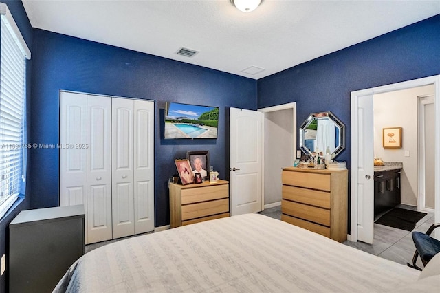 tiled bedroom with a closet and ensuite bathroom