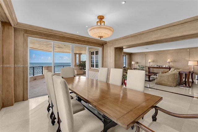 dining room with a water view, light tile patterned floors, and ornamental molding