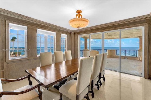 dining space featuring crown molding, a water view, and light tile patterned floors