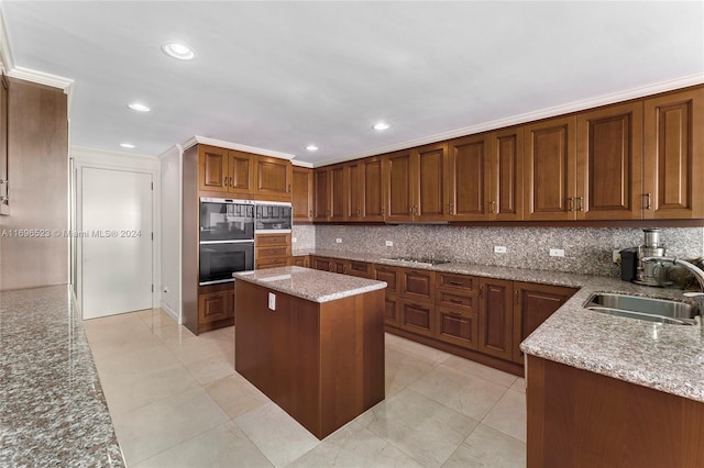 kitchen with backsplash, light stone counters, sink, and a kitchen island