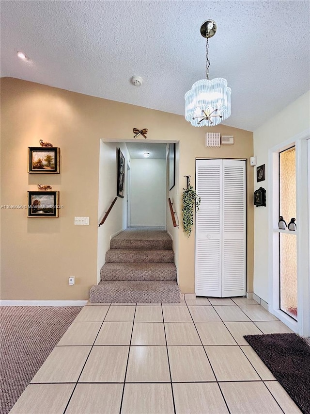 entryway with a textured ceiling, light tile patterned floors, a chandelier, and lofted ceiling