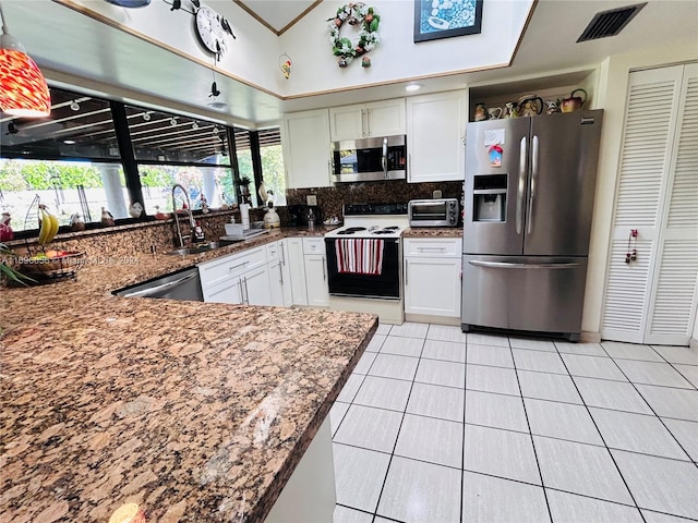 kitchen featuring appliances with stainless steel finishes, sink, light tile patterned floors, white cabinets, and lofted ceiling