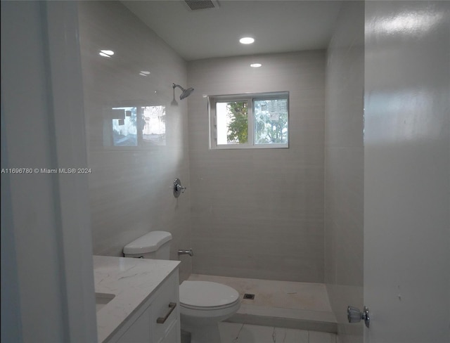 bathroom featuring vanity, tiled shower, and toilet