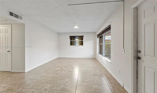 tiled empty room featuring a textured ceiling