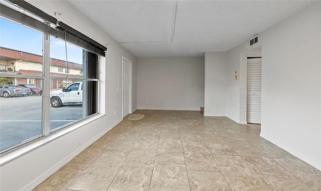 empty room with light tile patterned floors and a textured ceiling