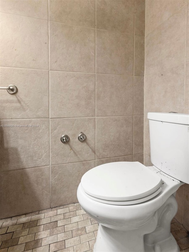 bathroom featuring tile walls and toilet