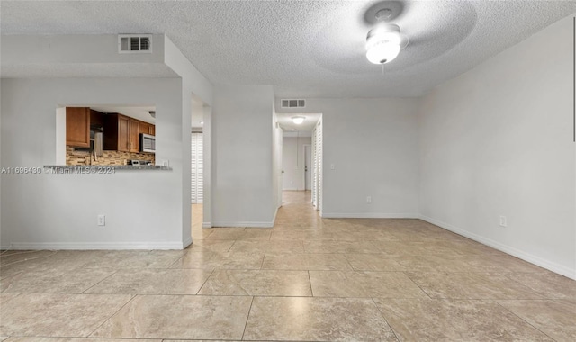 spare room with ceiling fan, light tile patterned floors, and a textured ceiling