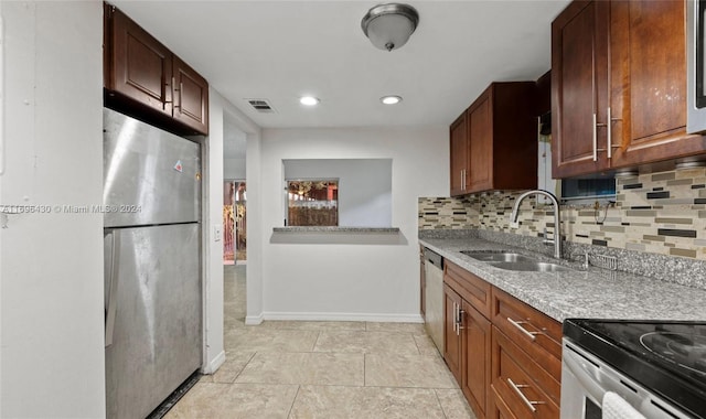 kitchen featuring decorative backsplash, stainless steel appliances, light stone countertops, and sink