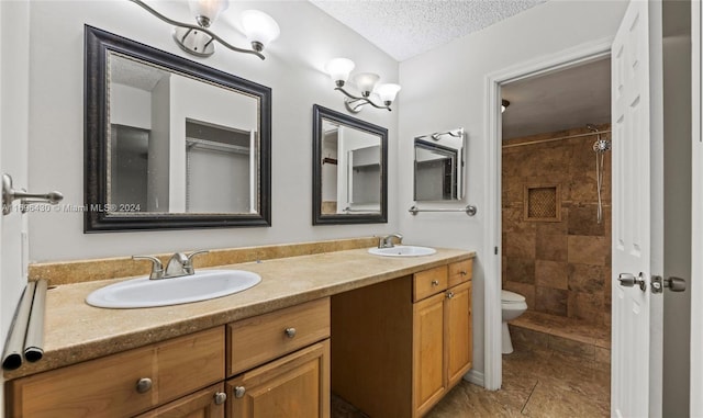 bathroom featuring tiled shower, vanity, a textured ceiling, and toilet