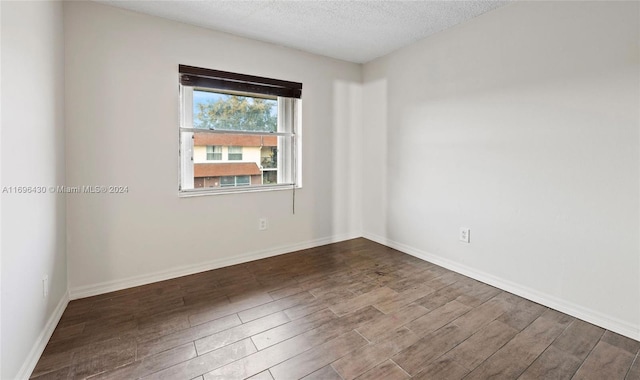 unfurnished room with dark hardwood / wood-style flooring and a textured ceiling