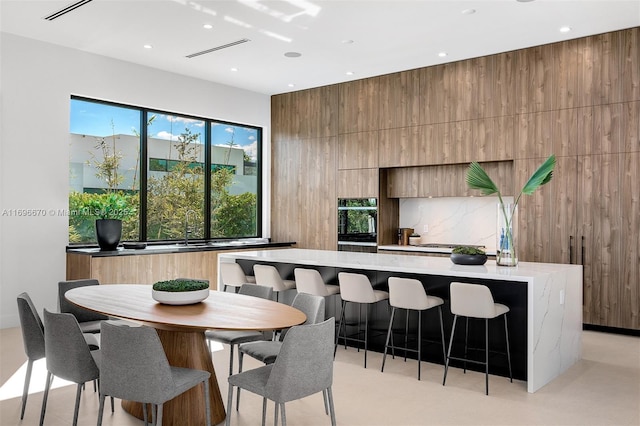 kitchen featuring a breakfast bar, black oven, a large island, and wood walls